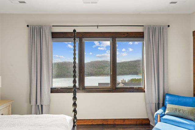 bedroom with visible vents, multiple windows, and wood finished floors