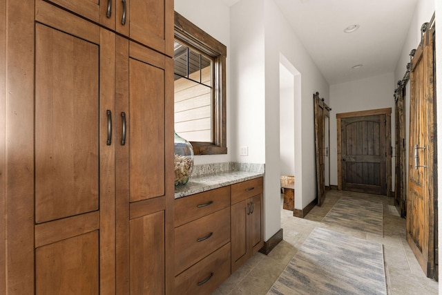 hallway with baseboards, recessed lighting, and a barn door