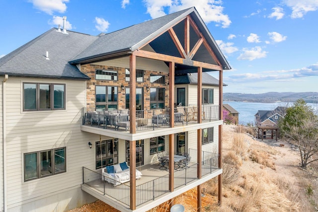 rear view of property featuring a mountain view, roof with shingles, a patio area, and a balcony