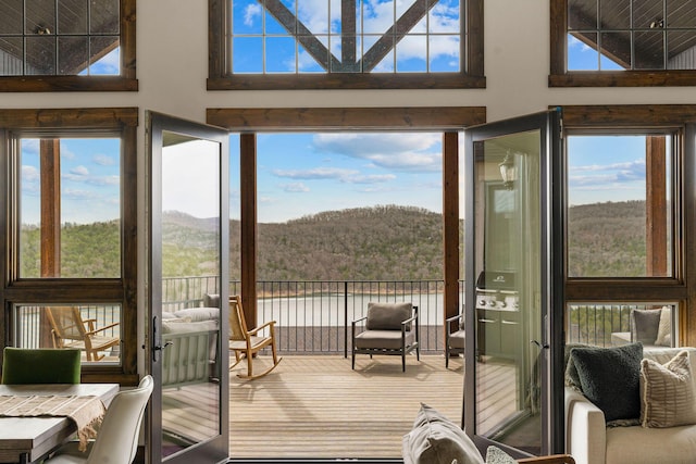 entryway featuring a water and mountain view, a towering ceiling, a forest view, and carpet floors