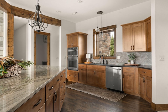 kitchen featuring dark wood-style flooring, a sink, stainless steel appliances, decorative light fixtures, and backsplash