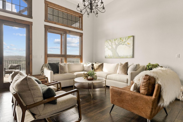 living area with a towering ceiling, dark wood-style floors, and an inviting chandelier