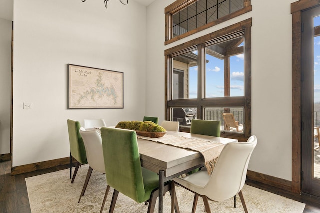 dining space with wood finished floors, an inviting chandelier, and baseboards