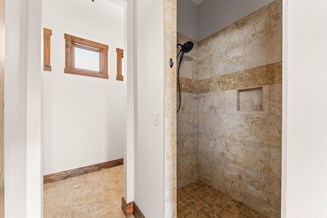 bathroom featuring tiled shower and baseboards
