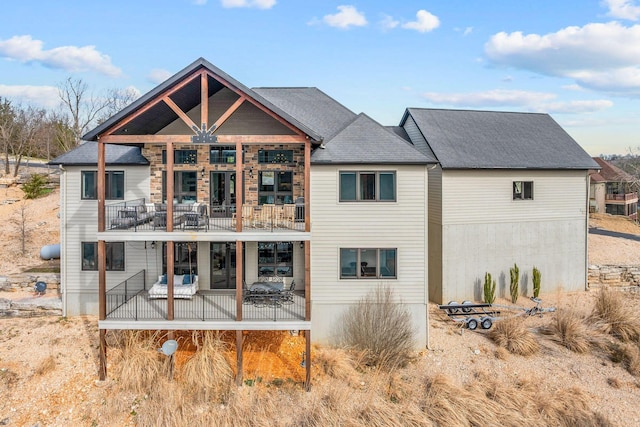 back of property with a balcony and a shingled roof