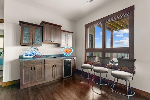 bar featuring indoor wet bar, visible vents, a sink, wine cooler, and baseboards