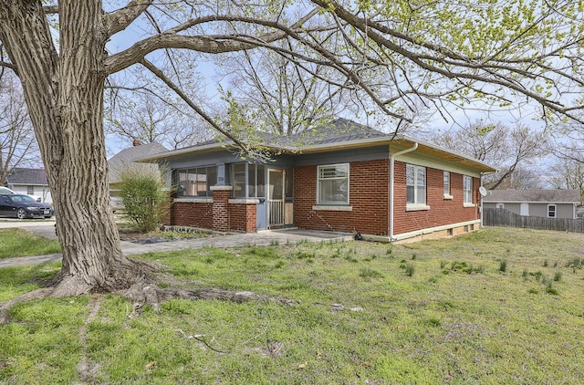 218 Lillian Pl, Bolivar, MO 65613 - bungalow with a sunroom, fence, a front lawn, brick siding, and a chimney