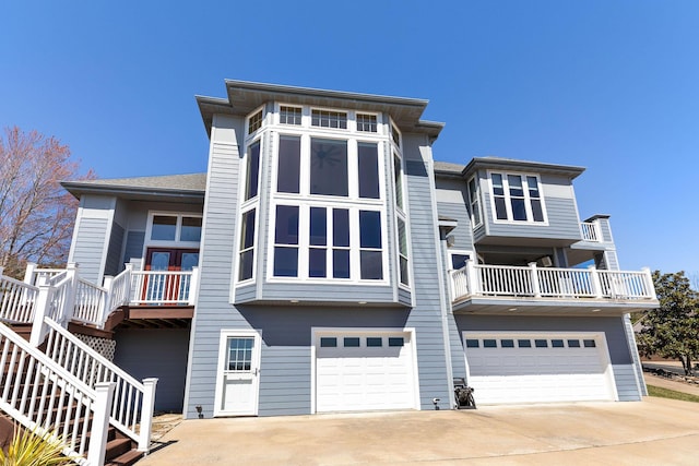 view of front of house featuring concrete driveway, a garage, and stairway