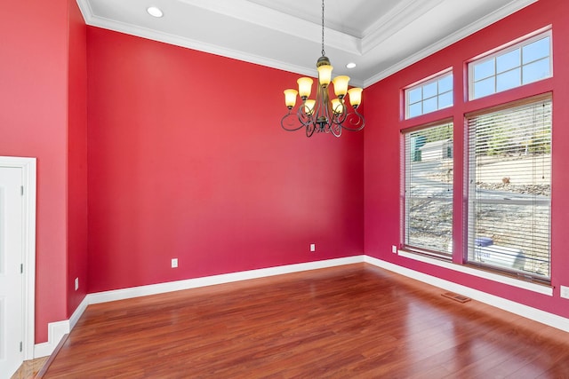 empty room with baseboards, visible vents, crown molding, and wood finished floors