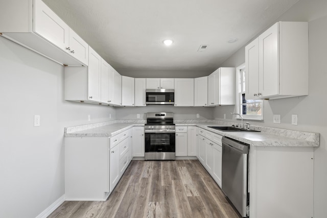 200 N Madison Ave, Mansfield, MO 65704 - kitchen with a sink, light wood-type flooring, stainless steel appliances, visible vents, and white cabinets