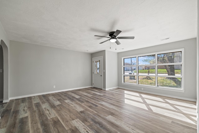 200 N Madison Ave, Mansfield, MO 65704 - unfurnished living room with baseboards, arched walkways, visible vents, a ceiling fan, and wood finished floors