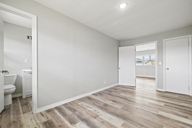 200 N Madison Ave, Mansfield, MO 65704 - unfurnished bedroom with connected bathroom, baseboards, and light wood-type flooring