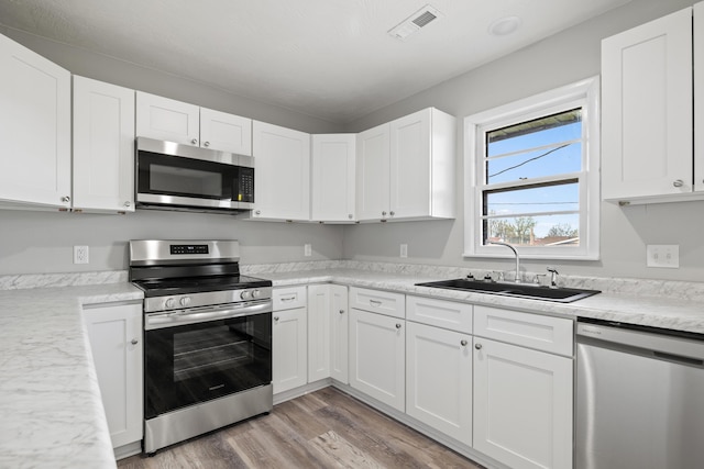 200 N Madison Ave, Mansfield, MO 65704 - kitchen featuring white cabinetry, light countertops, stainless steel appliances, a sink, and visible vents