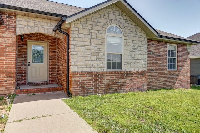 1471 Woodland Rd, Marshfield, MO 65706 - view of exterior entry with brick siding, stone siding, a lawn, and roof with shingles