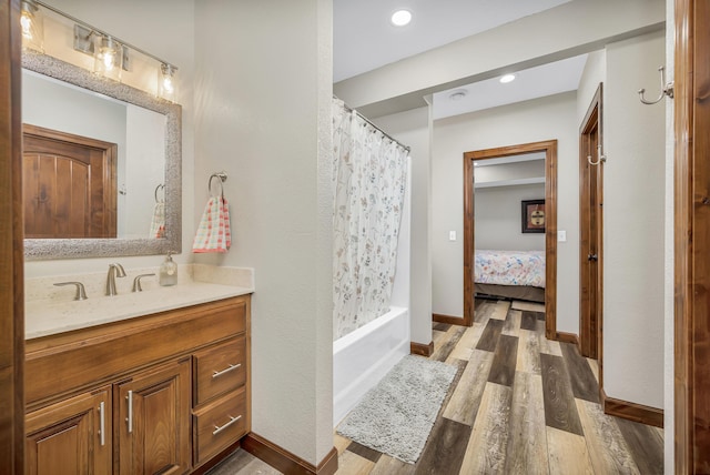 ensuite bathroom with baseboards, wood finished floors, recessed lighting, vanity, and shower / bath combination with curtain