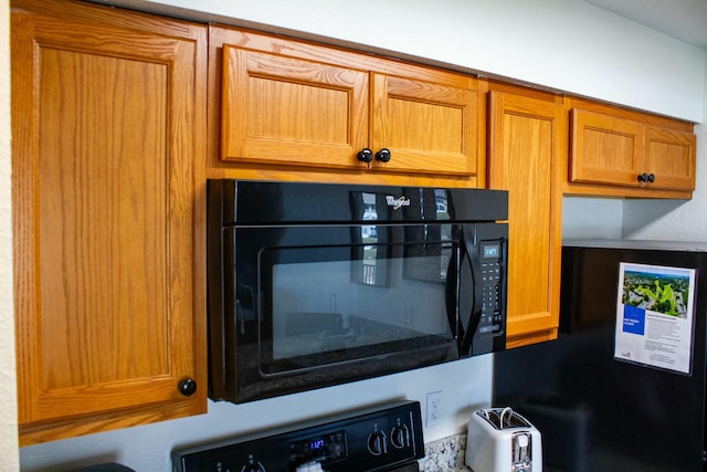 details featuring stove, black microwave, and brown cabinets