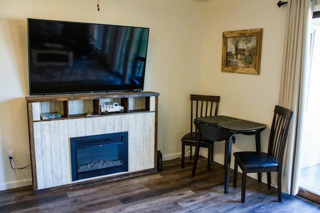 living area featuring a glass covered fireplace, baseboards, and wood finished floors