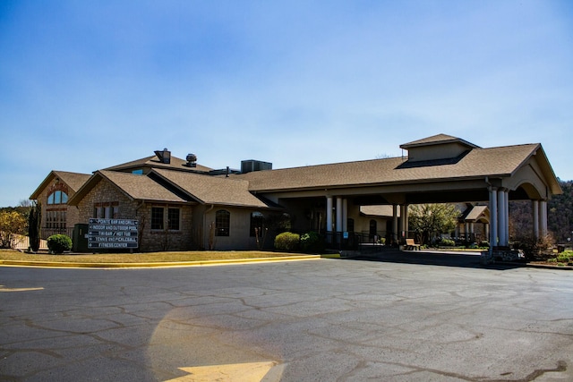 view of front of property with a chimney, a shingled roof, and stone siding