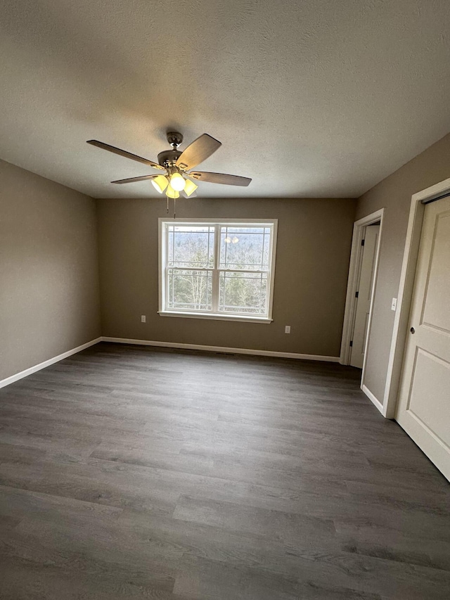 unfurnished room with dark wood-style flooring, a textured ceiling, baseboards, and ceiling fan