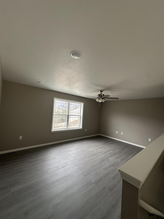 unfurnished living room featuring dark wood-style floors, baseboards, and ceiling fan