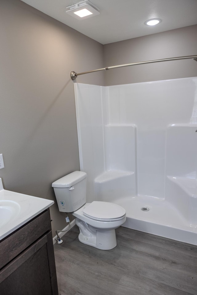 full bathroom featuring toilet, vanity, walk in shower, and wood finished floors