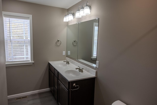 bathroom featuring wood finished floors, a sink, baseboards, and visible vents