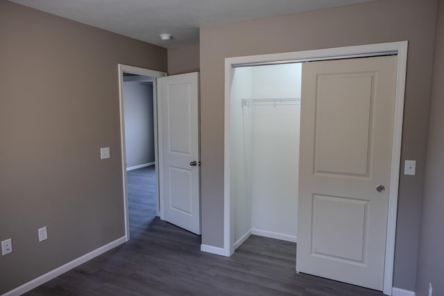 unfurnished bedroom featuring dark wood finished floors, baseboards, and a closet