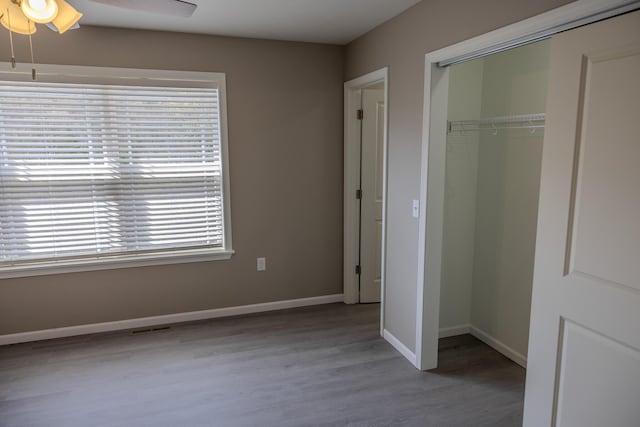 unfurnished bedroom featuring baseboards, a closet, wood finished floors, and ceiling fan