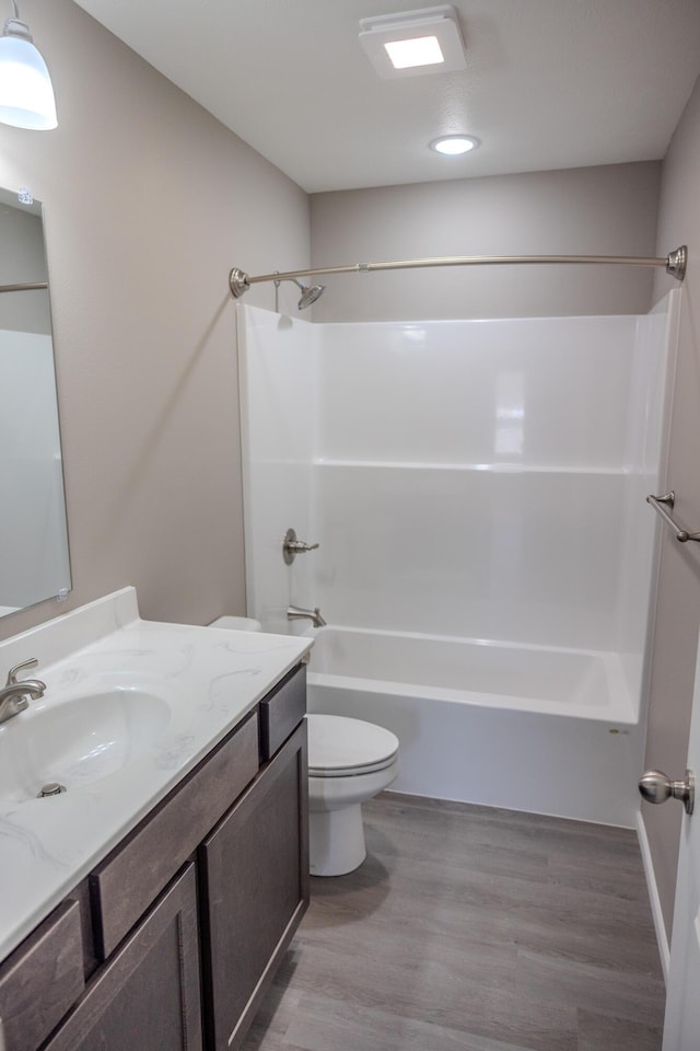 bathroom with toilet, vanity, shower / washtub combination, and wood finished floors
