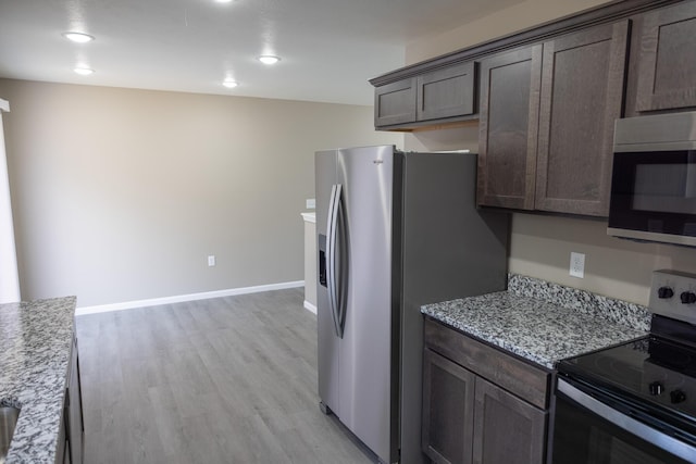 kitchen with dark brown cabinetry, appliances with stainless steel finishes, baseboards, and light wood-type flooring