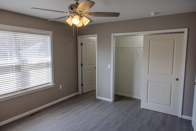 unfurnished bedroom with wood finished floors, baseboards, multiple windows, and visible vents