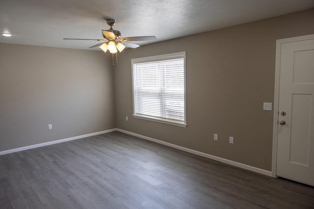 spare room featuring baseboards, wood finished floors, and a ceiling fan