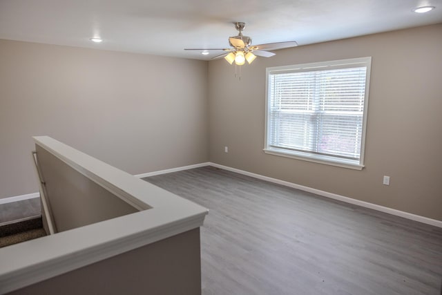 unfurnished room with a ceiling fan, recessed lighting, baseboards, and wood finished floors