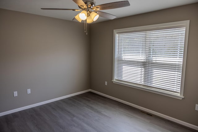 empty room with baseboards, visible vents, wood finished floors, and a ceiling fan
