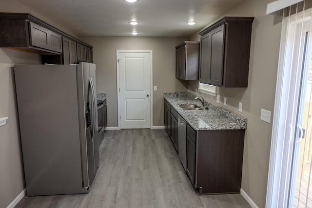 kitchen with dark brown cabinets, light wood finished floors, a sink, and stainless steel refrigerator with ice dispenser
