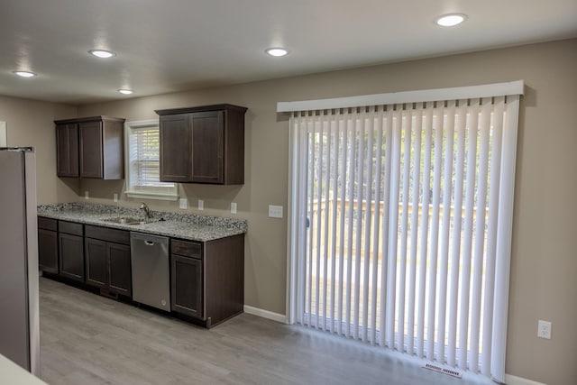 kitchen with dark brown cabinets, a sink, stainless steel appliances, and light wood finished floors