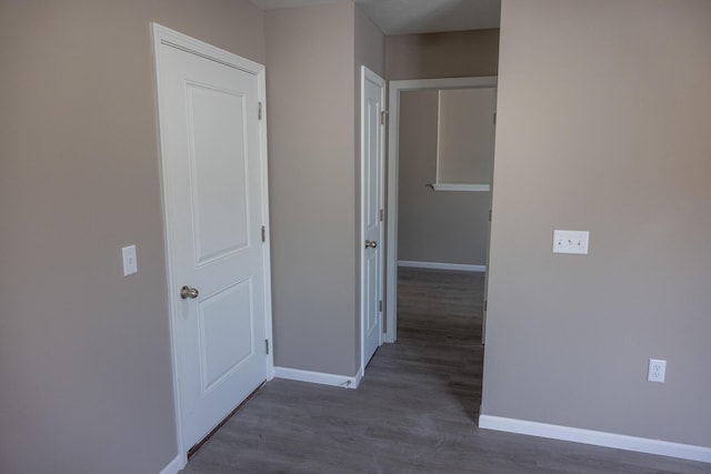 corridor featuring baseboards and wood finished floors