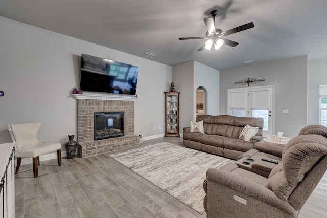 1859 Boyer Pl, Webb City, MO 64870 - living room featuring light wood finished floors, a fireplace, visible vents, arched walkways, and ceiling fan