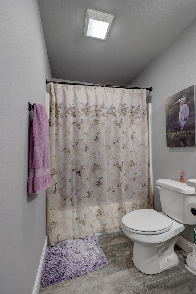 1859 Boyer Pl, Webb City, MO 64870 - bathroom featuring toilet, baseboards, a shower with shower curtain, and wood tiled floor