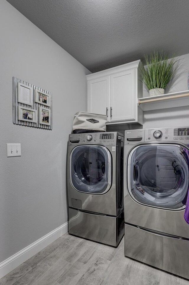 1859 Boyer Pl, Webb City, MO 64870 - laundry room with washing machine and clothes dryer, a textured ceiling, light wood finished floors, baseboards, and cabinet space