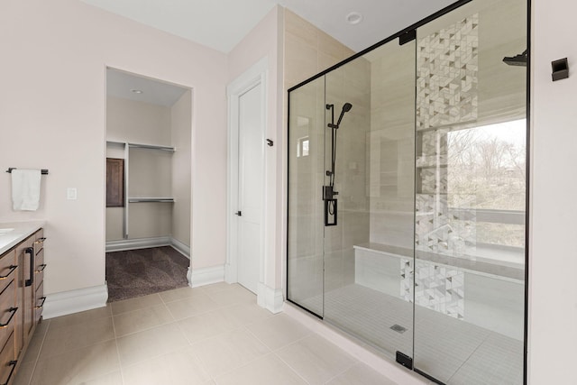 full bath with a stall shower, tile patterned floors, baseboards, and vanity
