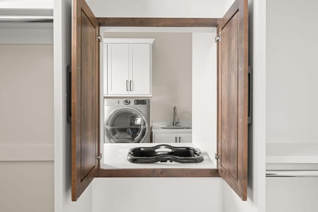 laundry room featuring cabinet space, a sink, and washer / dryer