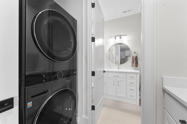laundry area with stacked washer and dryer, visible vents, laundry area, and a sink