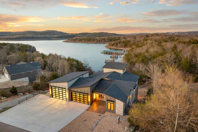 aerial view at dusk featuring a water view and a forest view