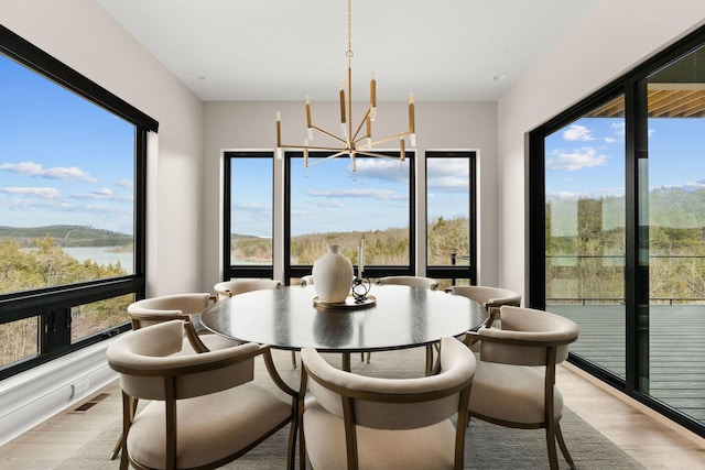 dining area featuring visible vents, a notable chandelier, a healthy amount of sunlight, and light wood-type flooring