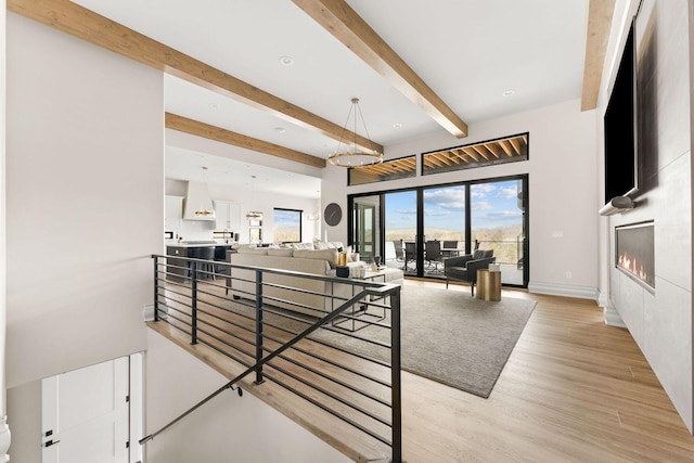 interior space featuring baseboards, a large fireplace, wood finished floors, and beamed ceiling