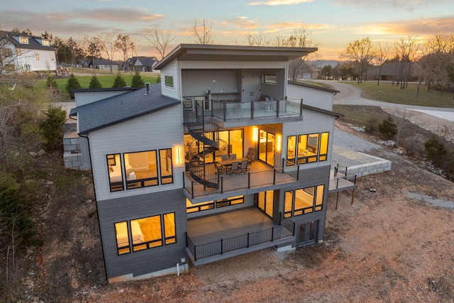 back of house at dusk with a balcony and stairway
