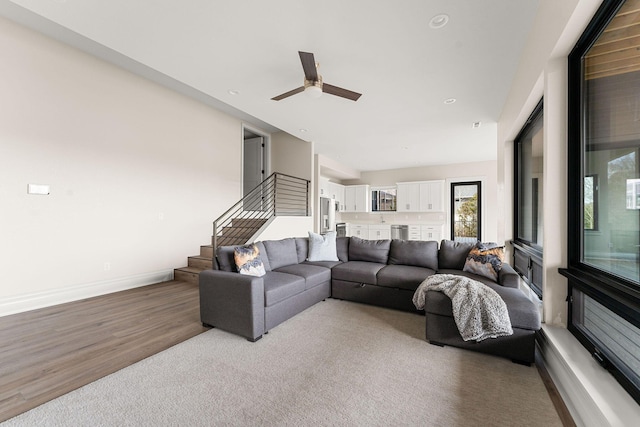 living room with stairs, wood finished floors, ceiling fan, and baseboards