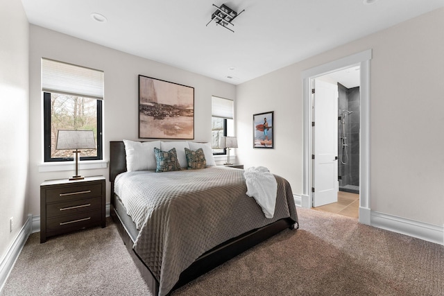 bedroom featuring light carpet, multiple windows, connected bathroom, and baseboards