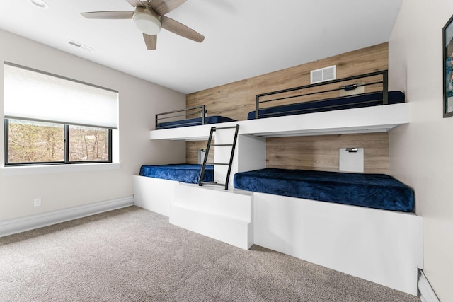 unfurnished bedroom featuring carpet floors, visible vents, wood walls, and a ceiling fan